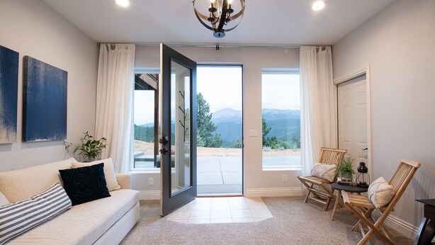 A spacious living room with a sofa, a coffee table, and a view of mountains through large sliding glass doors.