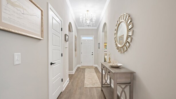 A hallway with white doors, a chandelier, and a mirror on the wall. - Gorgeous new home, one level & convenient location (Brunswick)