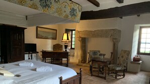 A traditional room with a large bed, wooden furniture, a stone fireplace, and a painting on the wall. - Waterfront manor house with heated pool (Baden)
