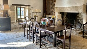 A rustic dining room with a wooden table, chairs, and a fireplace. - Waterfront manor house with heated pool (Baden)