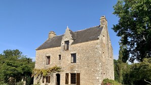A stone building with a symmetrical facade, two chimneys, and a central entrance. - Waterfront manor house with heated pool (Baden)