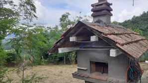 A rustic stone building with a sloped roof, a chimney, and a small window. - Easy Lake vacation home (Bargi)