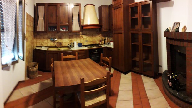 A kitchen with wooden cabinets, a dining table with chairs, a stove, and a fireplace. - Easy Lake vacation home (Bargi)