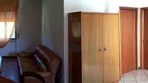 A room with a wooden wardrobe, a dining table with chairs, and a window with blinds. - Easy Lake vacation home (Bargi)