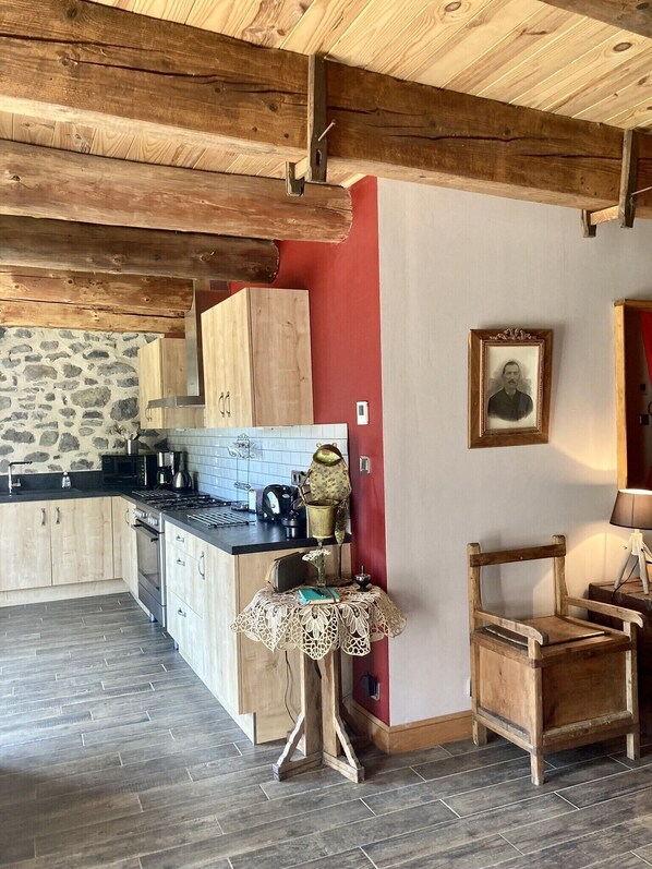 Une cuisine rustique avec des poutres en bois, un mur en pierre et un mur d’accent de couleur rouge.