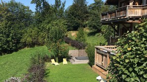 A wooden cabin with a stone staircase leading to a deck, surrounded by lush greenery and a clear blue sky. - Luxury apartment 14 people, with a nice view (Haute-Savoie)
