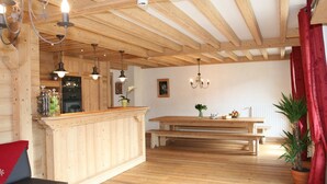 A wooden interior with a kitchen area, wooden beams on the ceiling, a dining table with benches, and potted plants. - Luxury apartment 14 people, with a nice view (Haute-Savoie)