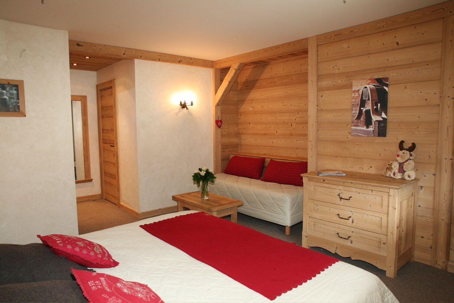 Een knus slaapkamer met een bed, nachtkastje, dressoir en een wandlamp.