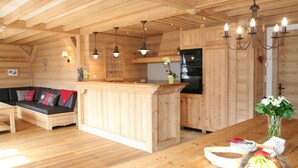 A wooden cabin interior with a kitchen, dining area, and a sofa. - Luxury apartment 14 people, with a nice view (Haute-Savoie)
