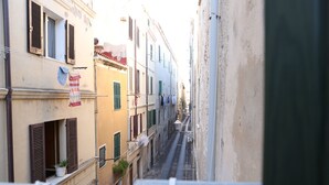 Une rue étroite, bordée de bâtiments des deux côtés, avec des balcons où le linge est étendu pour sécher.