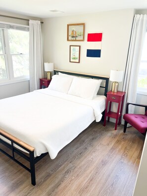 A neatly arranged bedroom with a large bed, two bedside tables, and a window with curtains. - Centrally Located DoCo Oasis (Fish Creek)