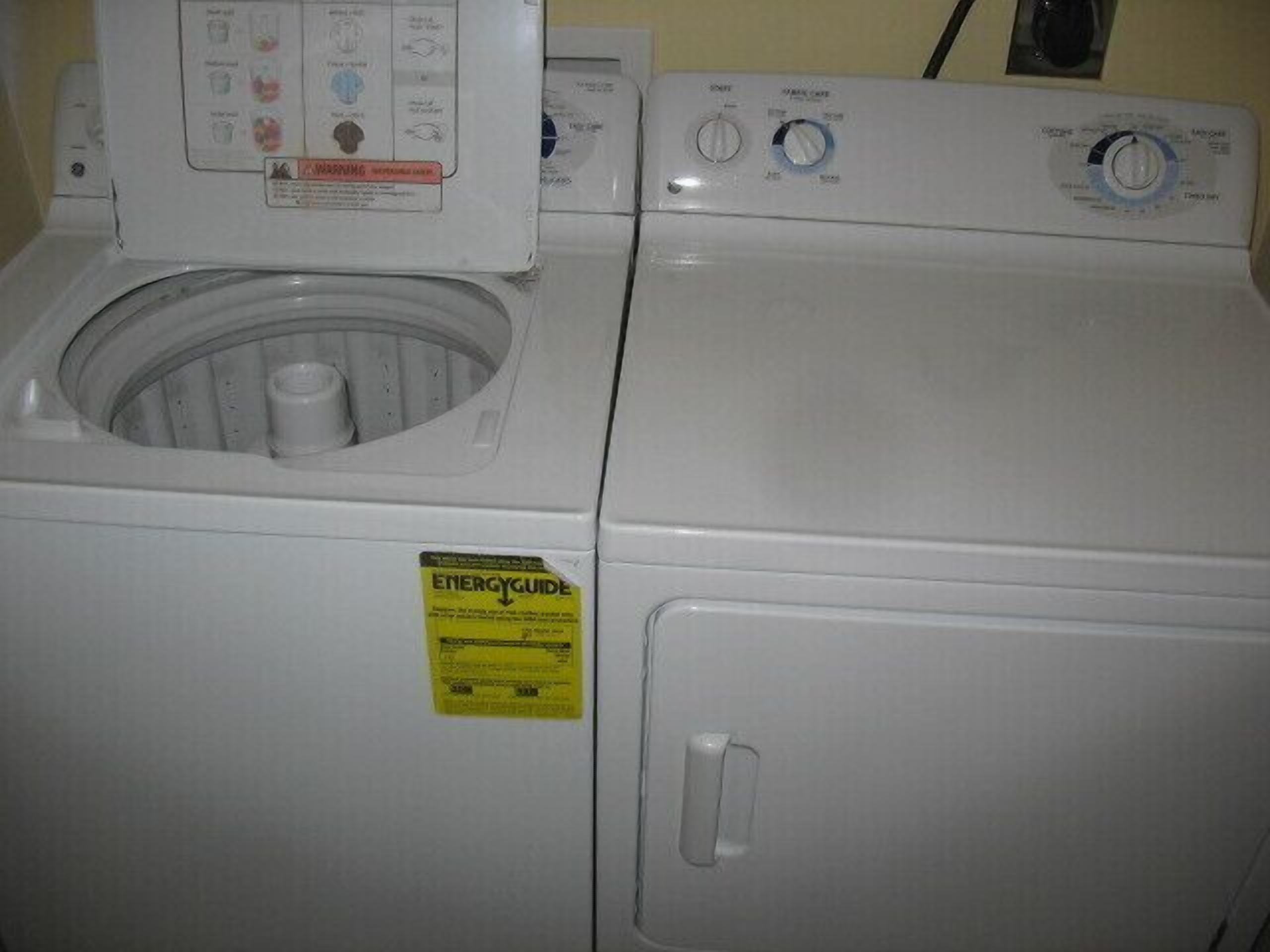A front view of a front-loading washing machine with a control panel and a yellow energy guide sticker.