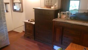 Eine Küche mit Holzausstattung, Fliesenboden und einem Schiffmodell auf den Schränken.