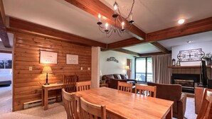 A cozy wooden interior with a dining table, chairs, a sofa, and a fireplace. - Comfortable Condo close to Slopes with a Hot Tub! (Mt. Crested Butte)