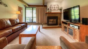 A cozy living room with a fireplace, a television, and a sofa. - Comfortable Condo close to Slopes with a Hot Tub! (Mt. Crested Butte)