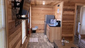 A compact wooden cabin with a kitchenette, a small dining area, and a sofa. - One Bedroom Cabin w/Sleeper Sofa Cabin 8 (Hamilton)