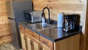 A compact kitchen with a stainless steel refrigerator, a microwave, a sink, and a coffee maker. - One Bedroom Cabin w/Sleeper Sofa Cabin 8 (Hamilton)
