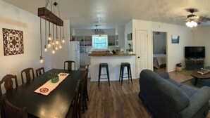 A spacious living area with a dining table, sofas, and a kitchen in the background. - On the Frio River (Leakey)