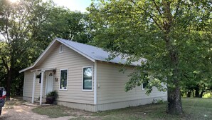 A small, single-story building with a gabled roof, a front porch, and a small front yard. - On the Frio River (Leakey)