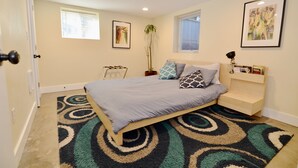 A bedroom with a bed, a window, a plant, and a framed picture on the wall. - Modern Suite Nearby Convention Center (2bd, 1bth) (Portland)