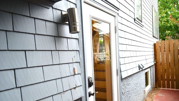 A house with a gray shingle exterior, a white door with a glass panel, and a small window. - Modern Suite Nearby Convention Center (2bd, 1bth) (Portland)