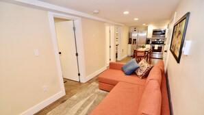 A living room with a sofa, a dining table, and a kitchen in the background. - Modern Suite Nearby Convention Center (2bd, 1bth) (Portland)