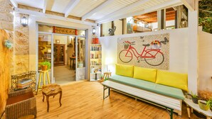 Un interior acogedor con piso de madera, un banco, una estantería y un mural de bicicletas en la pared.