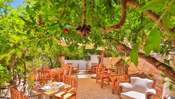 Un patio al aire libre con mobiliario de madera y una pared de piedra.