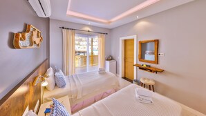 Habitación de hotel con dos camas, baño, balcón y vista a la ciudad.