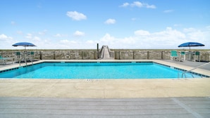 A rectangular swimming pool with a wooden deck in the foreground and a wooden fence in the background. - Sunset Serenade-Gulf Front Unit with Community Pool (Navarre)