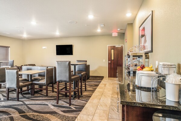 A hotel dining area with tables and chairs, a buffet station, and an exit sign.
