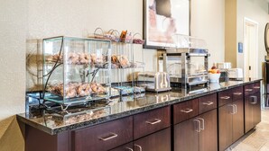 Een buffetopstelling met glazen vitrines, een koffiehoek en een schaal fruit.