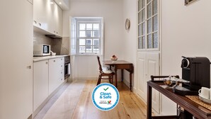 Una cucina angusta con mobili bianchi, un tavolo da pranzo in legno e una macchina per caffè.