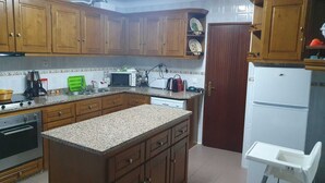 Eine Küche mit Holzausstattung, einer Granit Arbeitsplatte, einer Mikrowelle, einem Toaster und einem Kühlschrank.