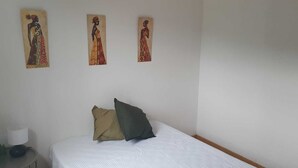 Ein Schlafzimmer mit einem Bett, zwei Kissen und drei an der Wand befestigten Bildern.