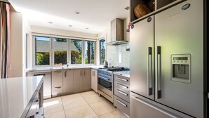 Una cocina moderna con un refrigerador de acero inoxidable grande, un horno empotrado y una estufa a gas.