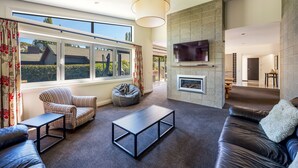 Una sala de estar moderna con sofá, sillón y mesa de centro, una chimenea y un televisor montado en la pared.