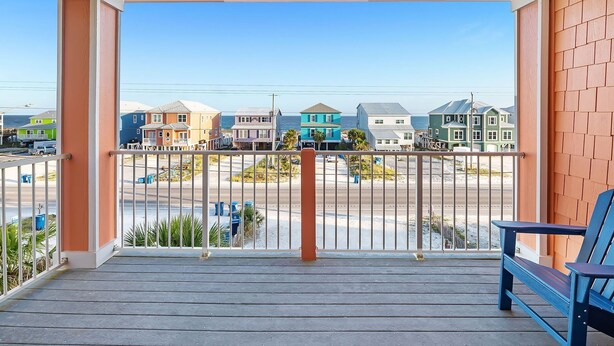 Een balkon met uitzicht op kleurrijke huizen en een strand.