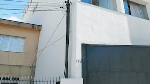 Un edificio moderno de varios pisos con fachada blanca, ventanas grandes y un garaje visible.