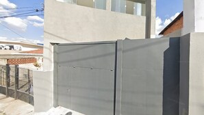 Una reja metálica gris con un candado de seguridad, unida a un muro de hormigón.