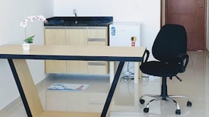 Un pequeño espacio de oficina con un escritorio, una silla y un refrigerador.