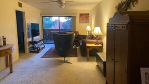 A living room with a modern chair, a wooden cabinet, and a ceiling fan. - Cozy 1 bedroom/1 Bathroom with large living room & kitchen. (Phoenix)