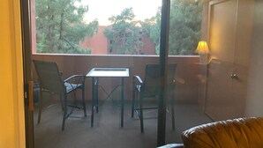 A balcony with a table and chairs, a door, and a view of trees and buildings. - Cozy 1 bedroom/1 Bathroom with large living room & kitchen. (Phoenix)