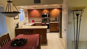 A kitchen with wooden cabinets, stainless steel appliances, a red plaid table with a Christmas decoration, and a floor lamp. - Cozy 1 bedroom/1 Bathroom with large living room & kitchen. (Phoenix)