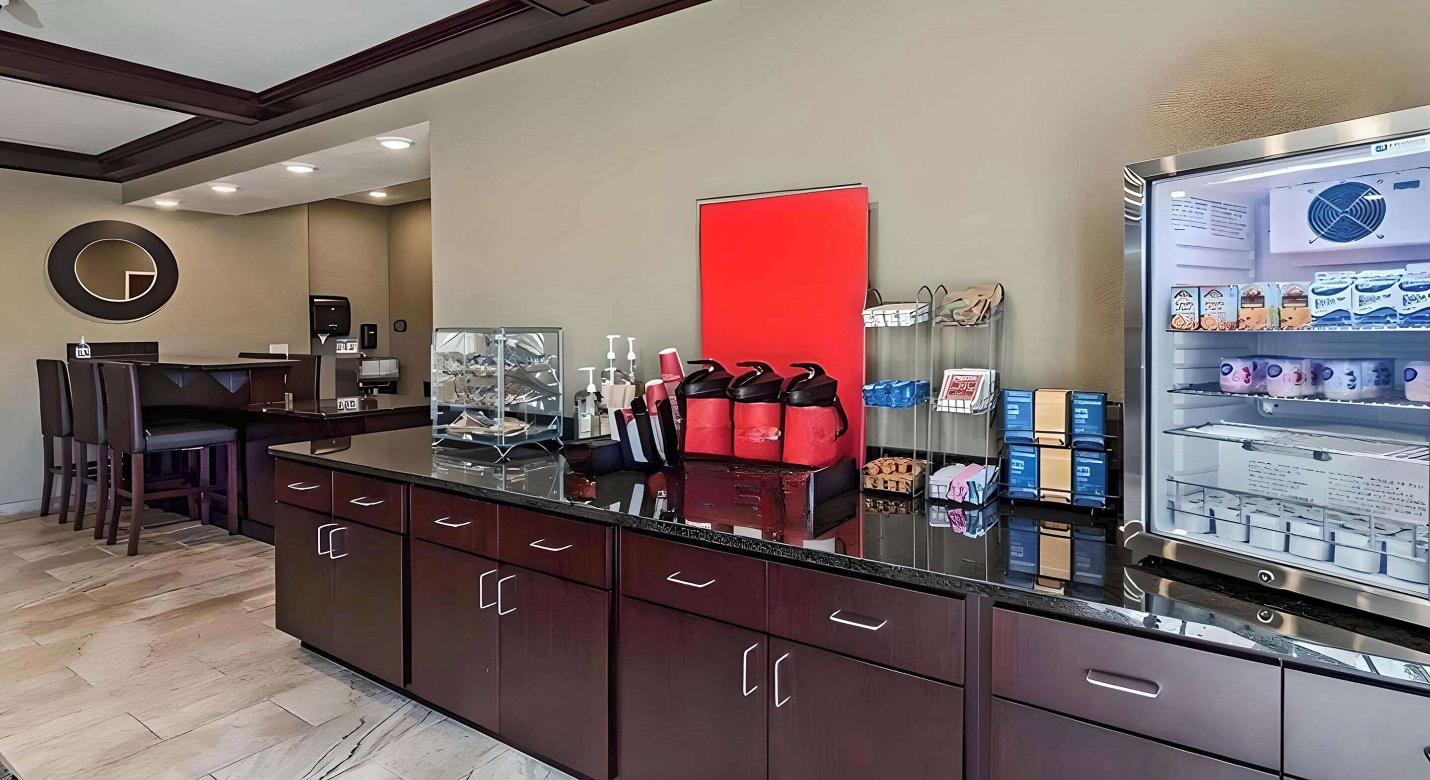 A reception area with a counter, a red accent wall, and a display case with various items.