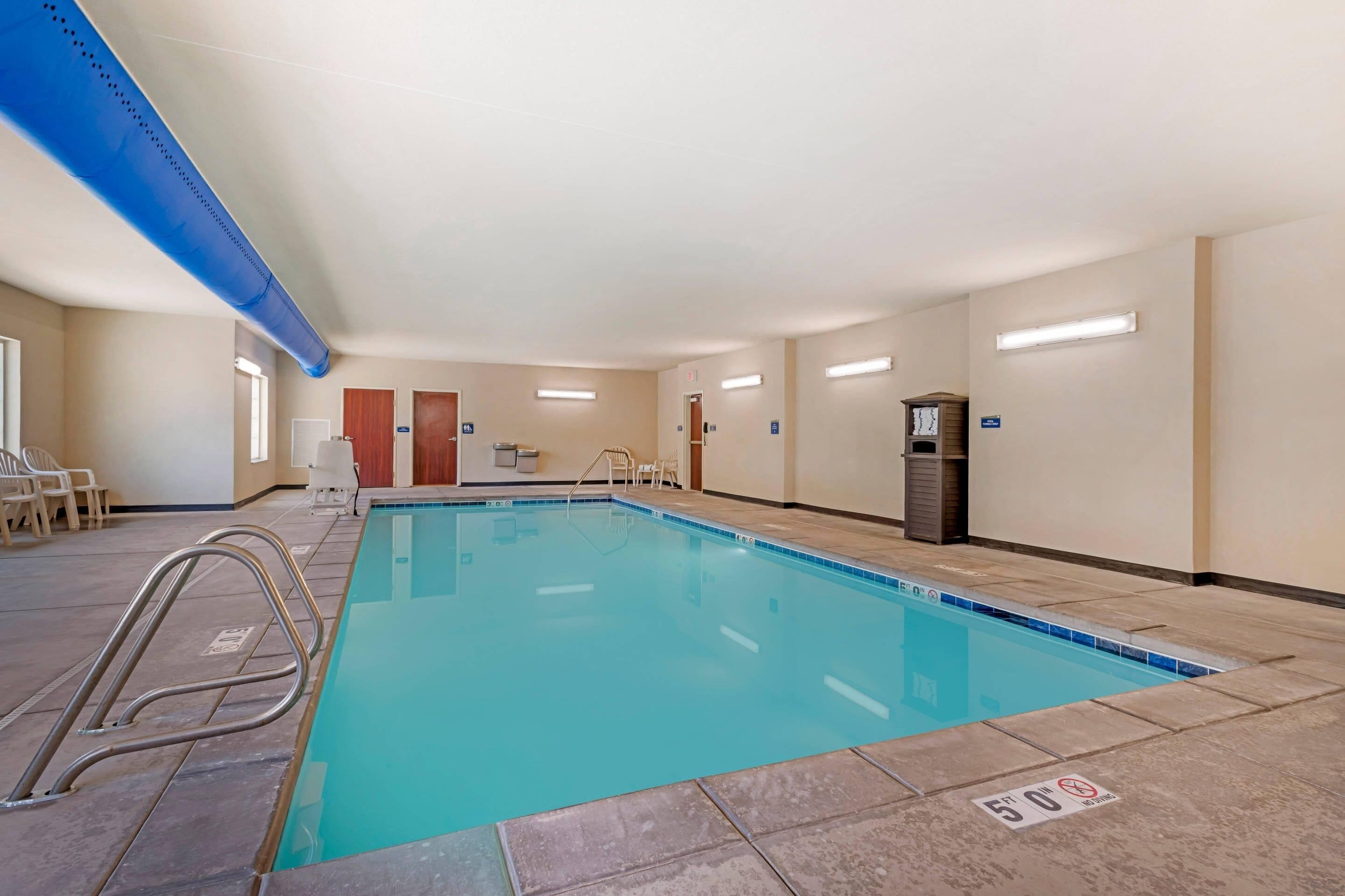 Une grande piscine intérieure à l’eau d’un bleu limpide, entourée d’un sol et de murs recouverts de carreaux.