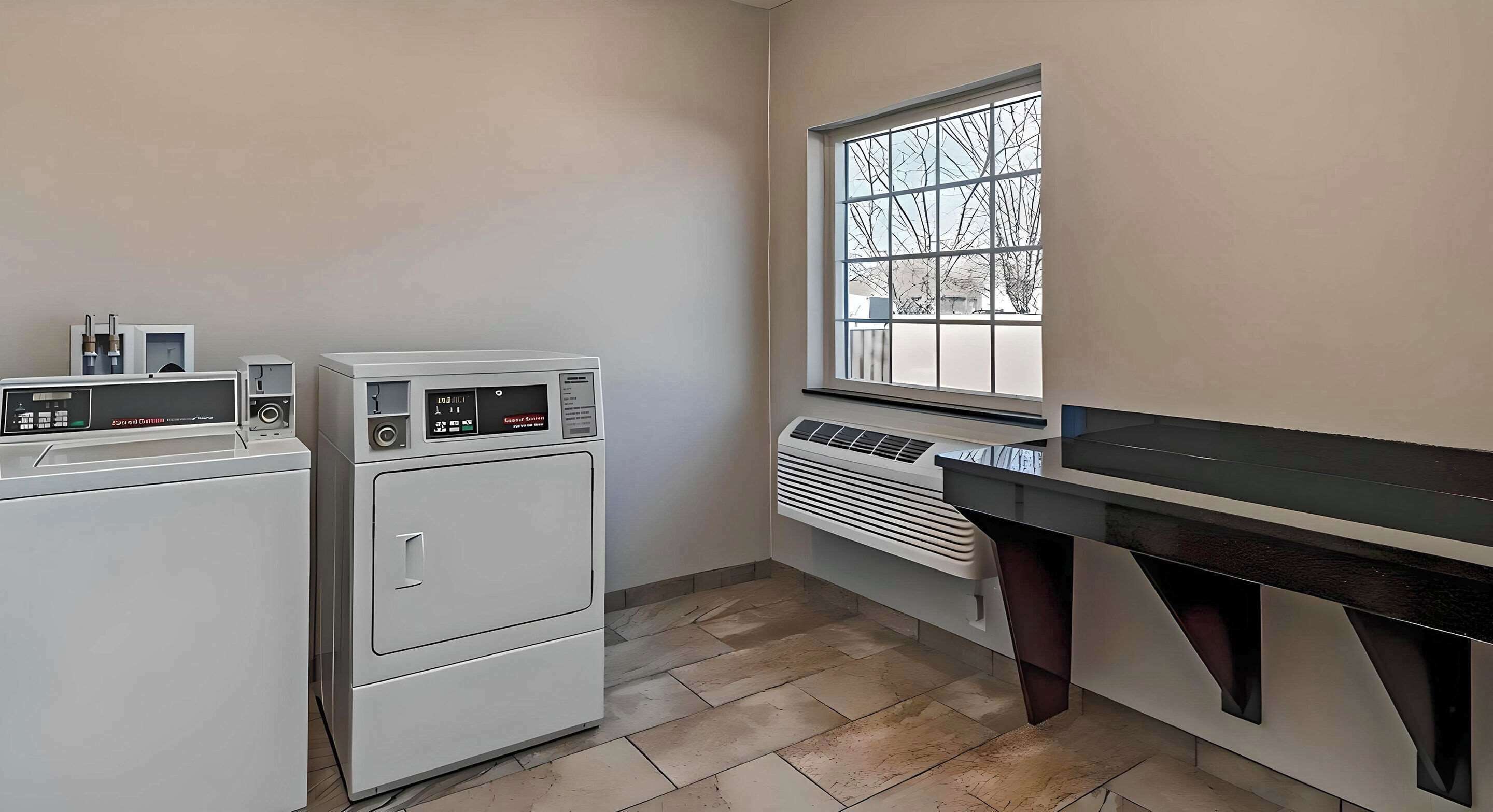 A laundry room with stacked washers and dryers, a window with a view, and a countertop with a sink.