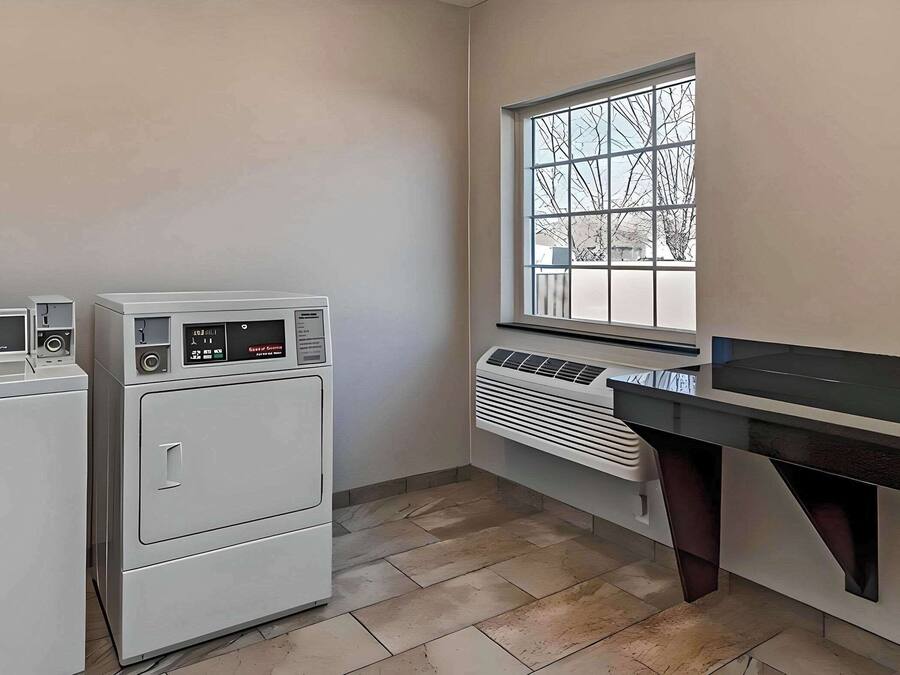 A laundry room with stacked washers and dryers, a window with a view, and a countertop with a sink.