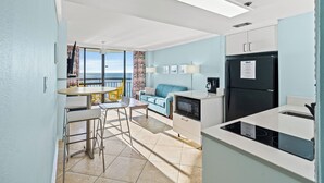 A modern kitchen with a black refrigerator, a microwave, and a dining area with a table and chairs. - 10th Floor 1br Oceanfront w/ Spectacular Views! (Myrtle Beach)
