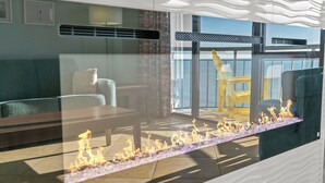 A modern living room with a glass partition, a sofa, a table, and a view of the sea. - 10th Floor 1br Oceanfront w/ Spectacular Views! (Myrtle Beach)